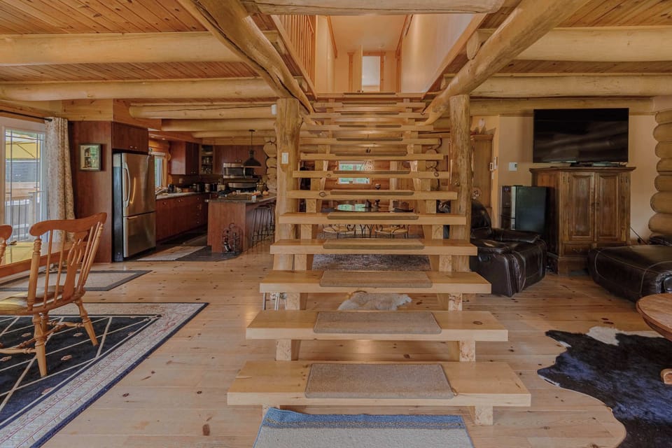 Open living area with wood beams, cozy seating, and a modern staircase