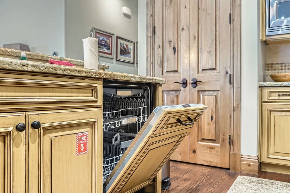 Prepare gourmet meals in this elegant, traditional kitchen. Featuring light wood cabinetry, a grand range hood, and a sprawling granite island, it's a chef's dream with high-end appliances.
