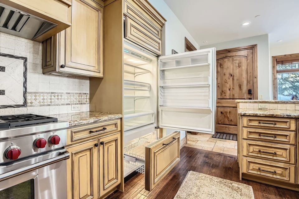 Prepare gourmet meals in this elegant, traditional kitchen. Featuring light wood cabinetry, a grand range hood, and a sprawling granite island, it's a chef's dream with high-end appliances.
