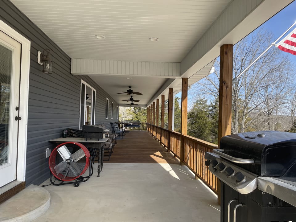 Large porch with a gas grill, blackstone, charcoal grill and fan.