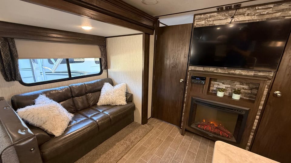 Living area has faux leather couch, Smart TV, fireplace & in/outdoor speakers.