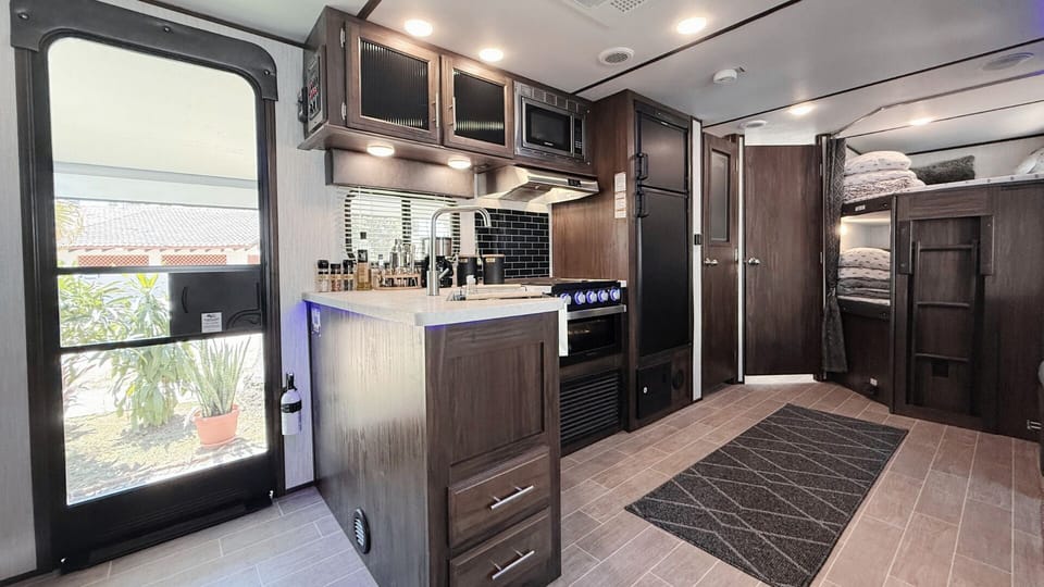 Fully equipped kitchen with gas stove, microwave, fridge, sink, and pantry.