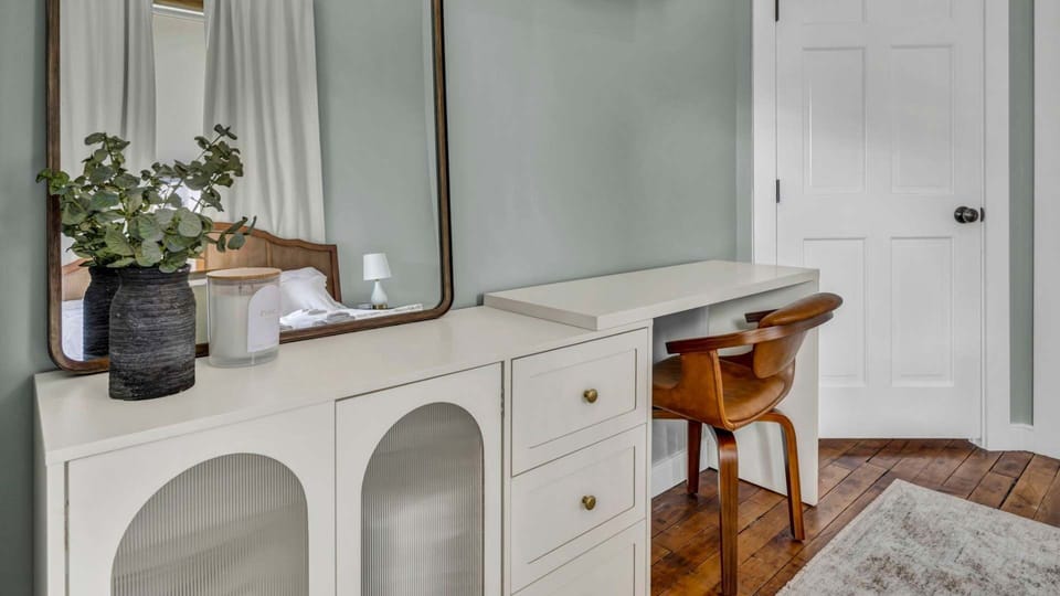 The king bedroom features a sleek dresser with ample storage, its clean lines complementing the industrial style. A small plant sits atop, adding a touch of greenery and warmth to the modern, minimalist space.