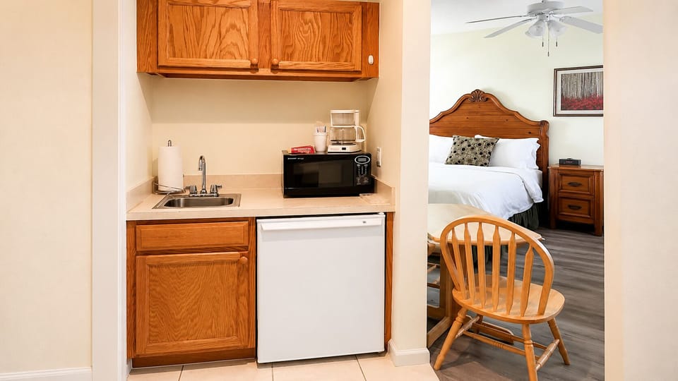 Convenient kitchenette area with sink, microwave, mini fridge, cabinet storage, and in-room seating.