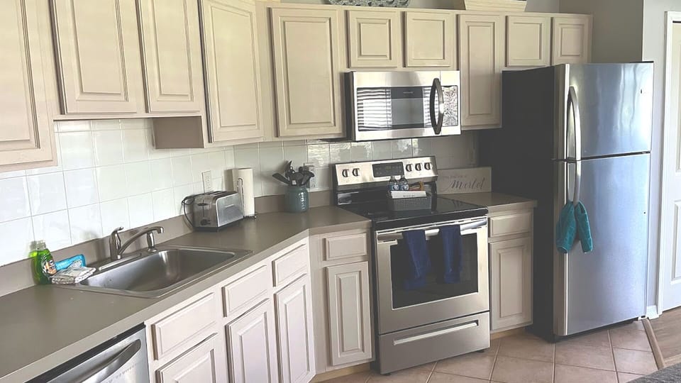 Updated kitchen featuring light cabinetry, stainless steel appliances, tile backsplash, and convenient counter space.