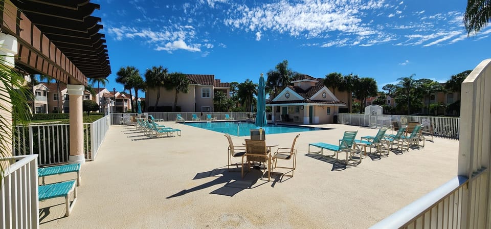 Bright community pool area with lounge seating, umbrellas, and a relaxing resort-style feel.
