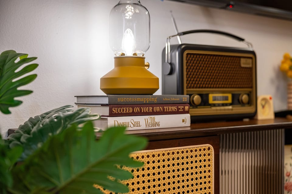 Retro-style radio speaker and lamp on media console with books.