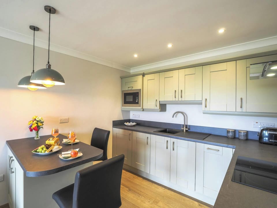 Kitchen with breakfast bar and dining stools, kitchen units, sink and hob