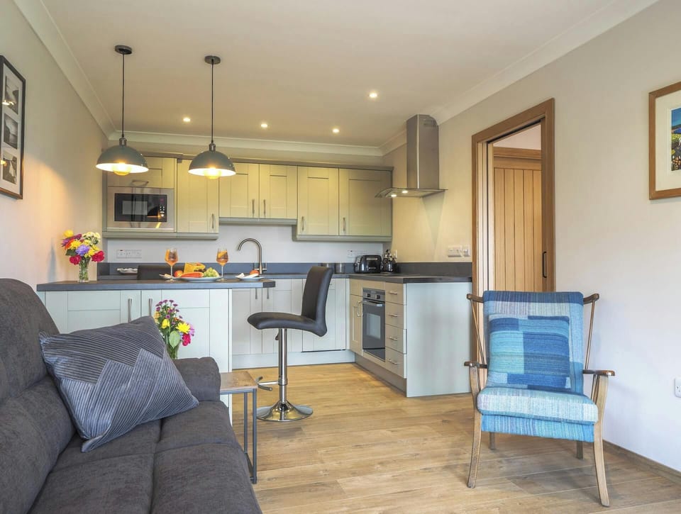 Living area with sofa, armchair, kitchen, breakfast bar and dining stools