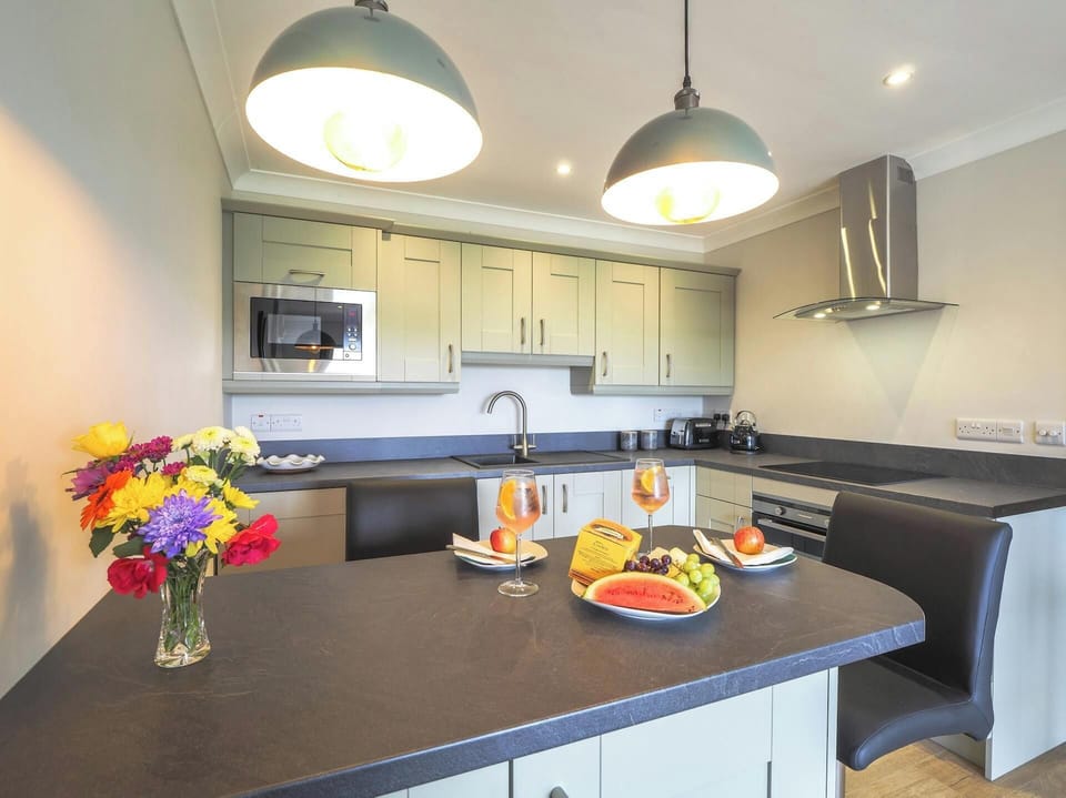 Breakfast bar and kitchen, vase of flowers, fruit and drinks