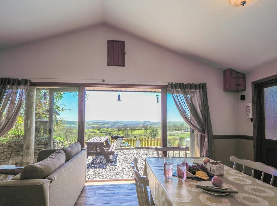 Dining area with table and chairs, double doors leading to patio with picnic bench