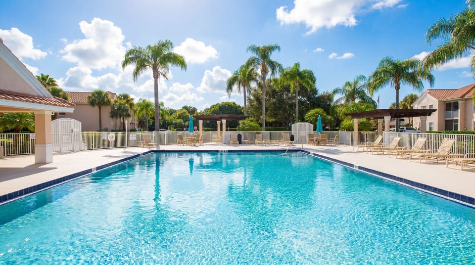 Bright community pool area with lounge seating, umbrellas, and a relaxing resort-style feel.