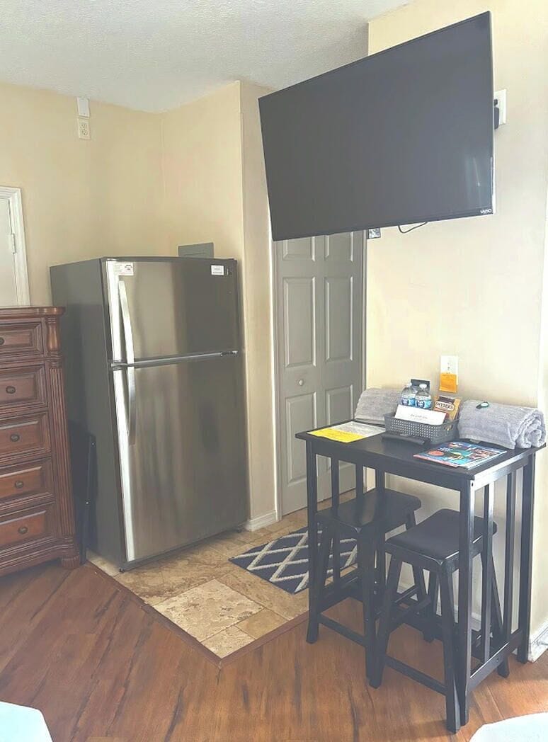 Bedroom sitting area with TV, dresser storage, mini fridge, and a small dining/work table.