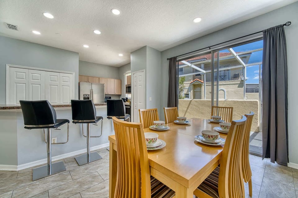 Dining area with wooden table set for six and sliding doors leading to a private patio.