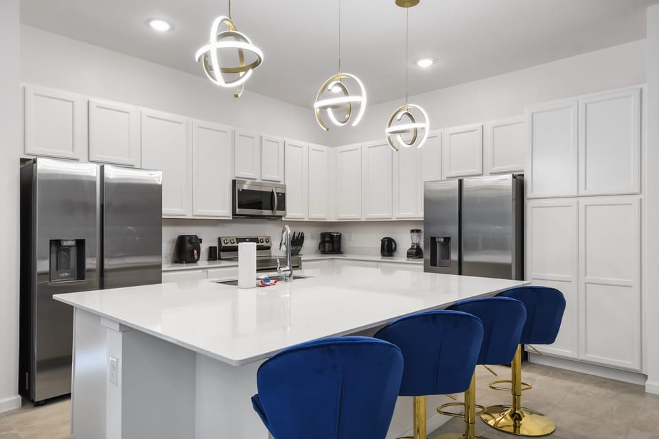 Sleek kitchen with stainless steel appliances, bold lighting, and island seating.