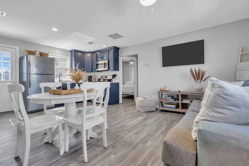 Open kitchen and dining with white round pedestal table, four chairs, and adjacent navy cabinetry.