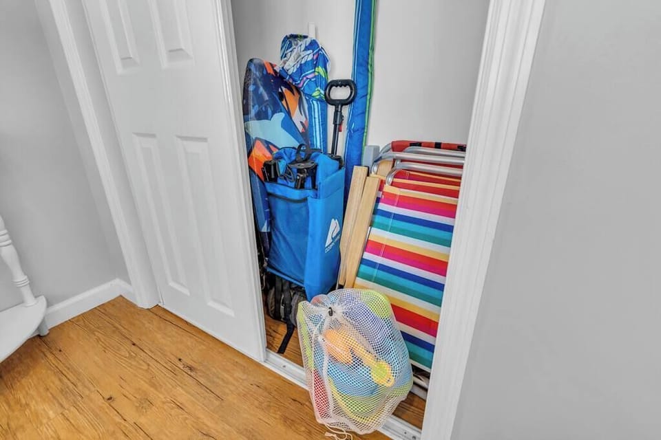Beach gear closet with stacked totes, beach chairs, towels, and folded umbrellas.