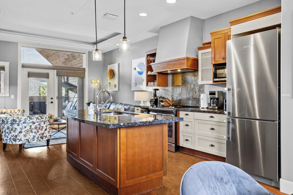 The kitchen opens to cozy living area with large windows and stylish lighting. 