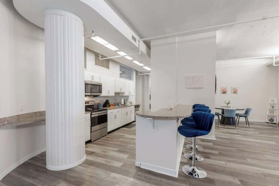 - Sleek kitchen layout with modern appliances and bright white cabinets 
- Spacious counters and bar seating great for meals and cooking 
- Open layout offering convenience for guests enjoying extended stays 
