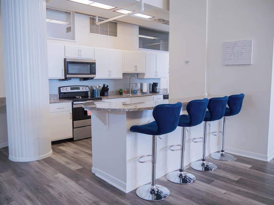 - Sleek kitchen with stainless appliances and spacious countertops 
- Breakfast bar with bold blue stools creating a welcoming dining spot 
- Fully equipped cooking space ideal for extended stays downtown 
