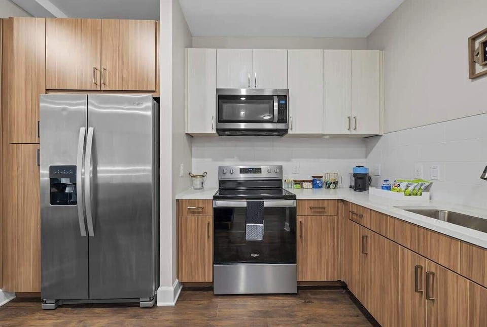 - Modern kitchen with stainless appliances and wood cabinets  
- Fully equipped cooking space ideal for extended Airbnb stays  
- Clean countertops and bright lighting make meal prep easy  