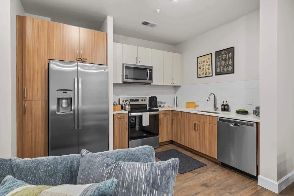 - Sleek shared kitchen with stainless fridge oven microwave and wood cabinets  
- Perfect setup for longer stays meal prep and daily cooking ease here  
- Open layout connects smoothly to living area for guest convenience