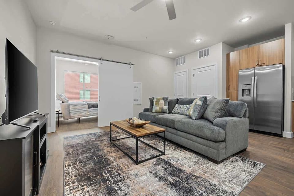 - Cozy living room with soft sofa large TV bright lighting and open flow  
- Perfect relaxation spot after exploring nearby city hotspots and fun  
- Inviting layout connects smoothly to kitchen and bedroom for comfort
