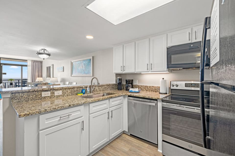 Fully equipped kitchen with a full refrigerator and freezer, stove with 4 burners and oven, microwave, dishwasher, and sink. Features granite countertops, ample cabinet space, plus both Keurig and drip coffee makers for added convenience.