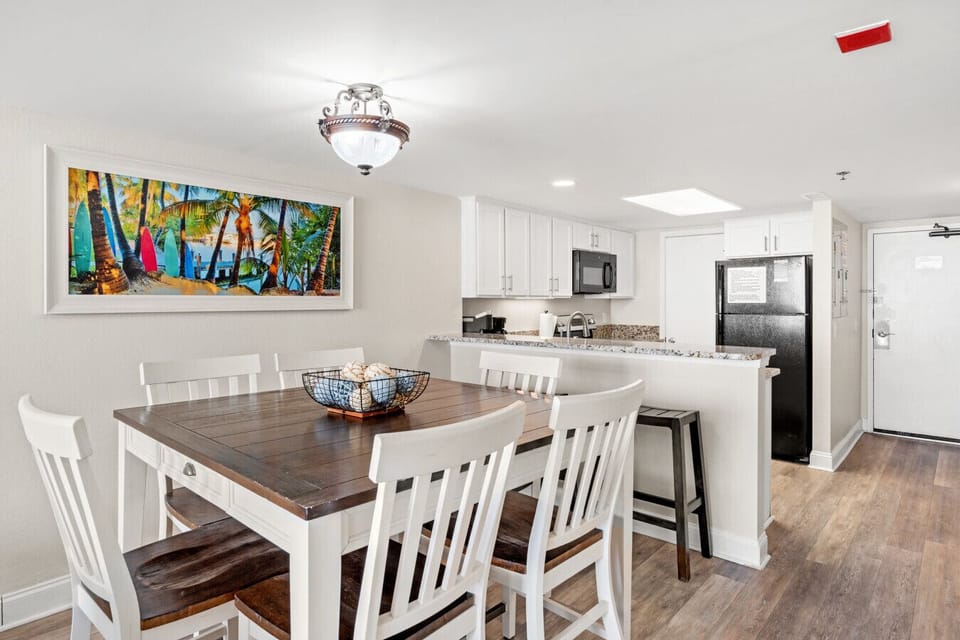 Open dining area filled with natural light, featuring seating for 6 at the table and 2 at the bar. The open floor plan offers easy kitchen access and beautiful oceanfront views for meals, games, or gatherings.
