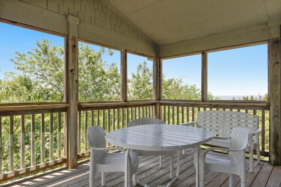 Settle into your private screened porch where fresh air meets comfort. Sip morning coffee at this serene outdoor dining spot framed by lush treetops and peaceful countryside.