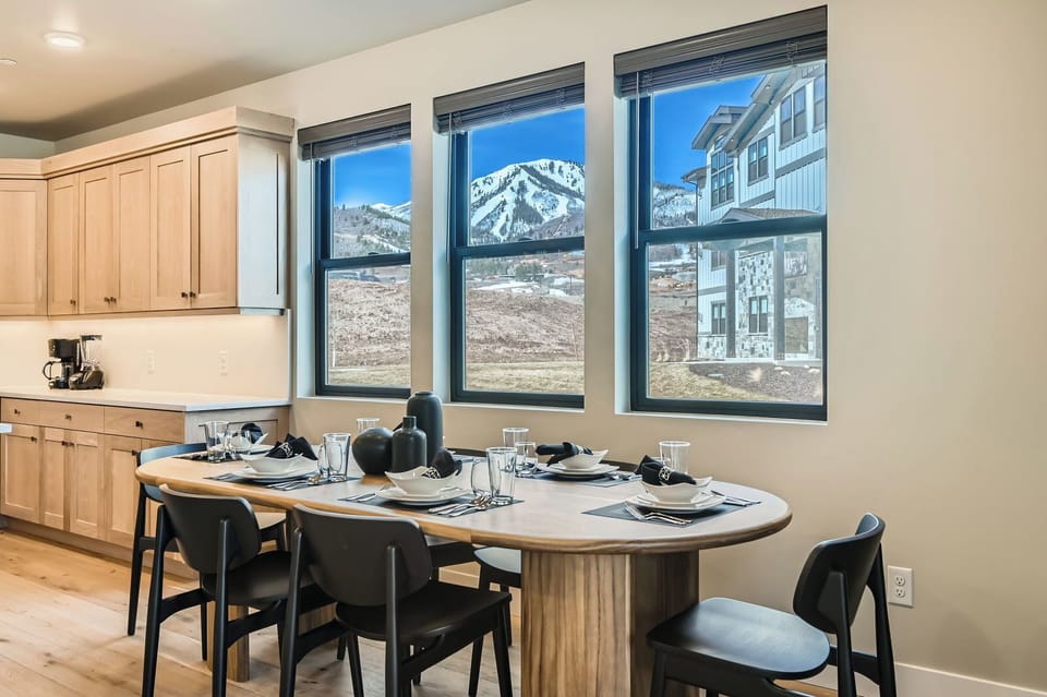 Host large groups in this modern Park City dining area featuring an oval wooden table for six. Large windows frame stunning ski slope views—the perfect year-round alpine retreat!