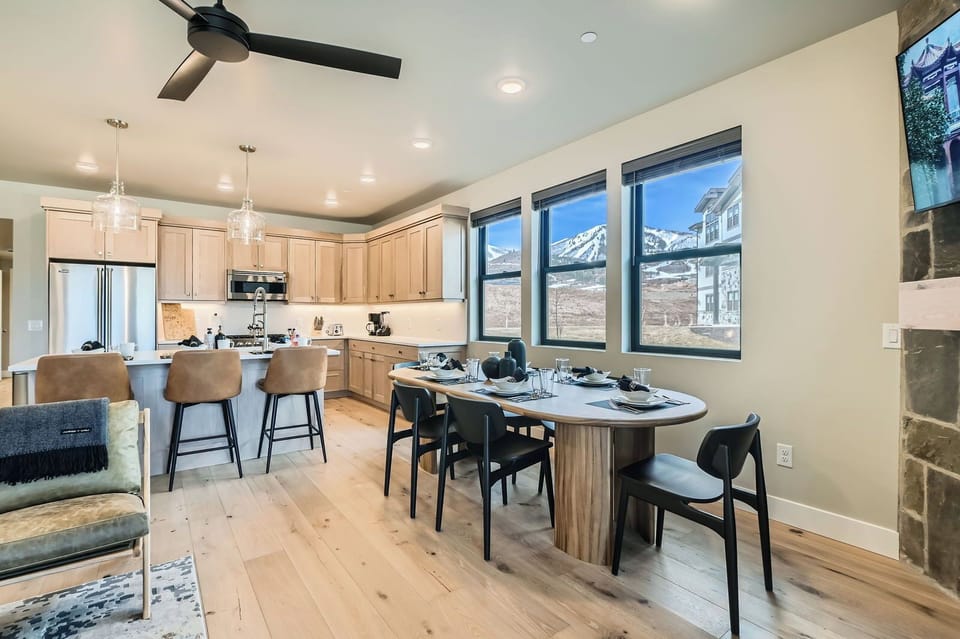 Host large groups in this modern Park City dining area featuring an oval wooden table for six. Large windows frame stunning ski slope views—the perfect year-round alpine retreat!