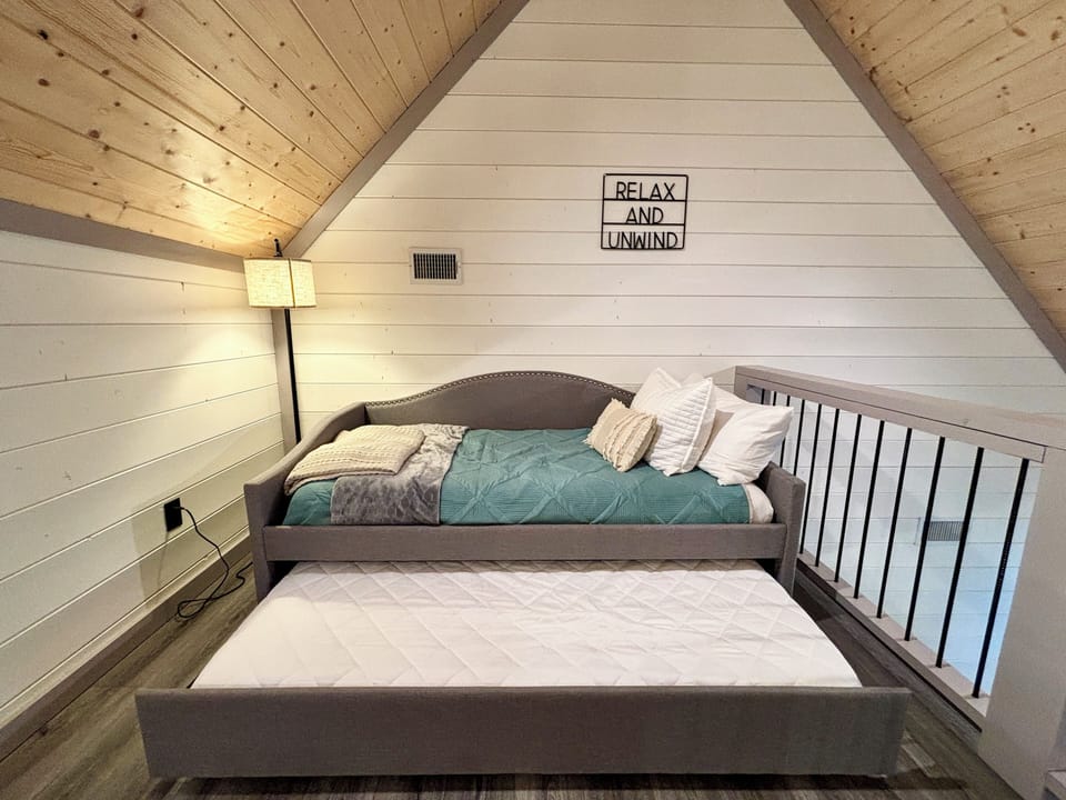 Unwind in this cozy loft bedroom with a stylish trundle bed, soft lighting