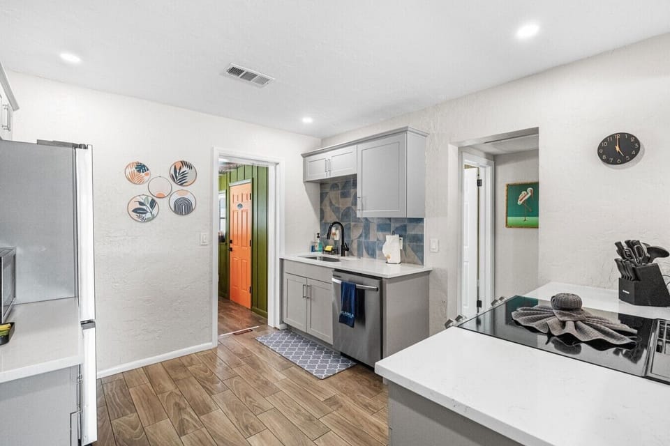 Kitchen — stainless dishwasher, geometric tile backsplash, grey shaker cabinets, full-size refrigerator. 4-bedroom vacation rental, St. Pete, FL.