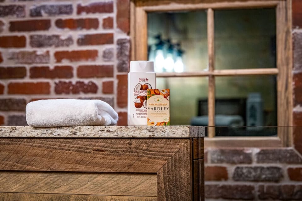 Rustic meets refined in this full bath with exposed brick, wood textures, and a stone-floor walk-in shower designed for both comfort and character.