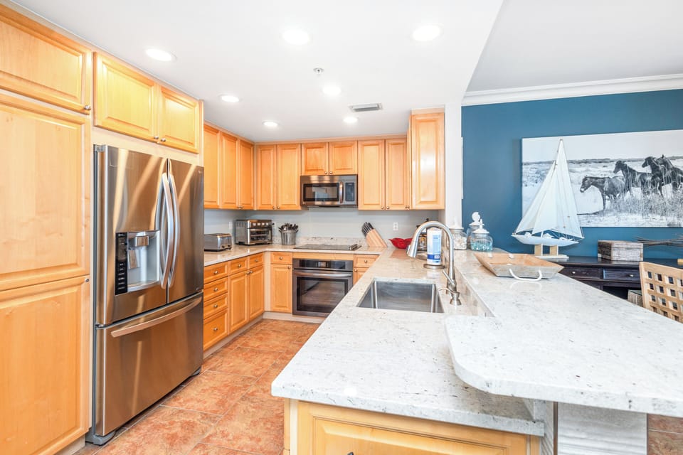 Your gourmet kitchen awaits with gleaming granite countertops, stainless steel appliances, and warm wood cabinetry—perfect for preparing meals after a day exploring the coast.