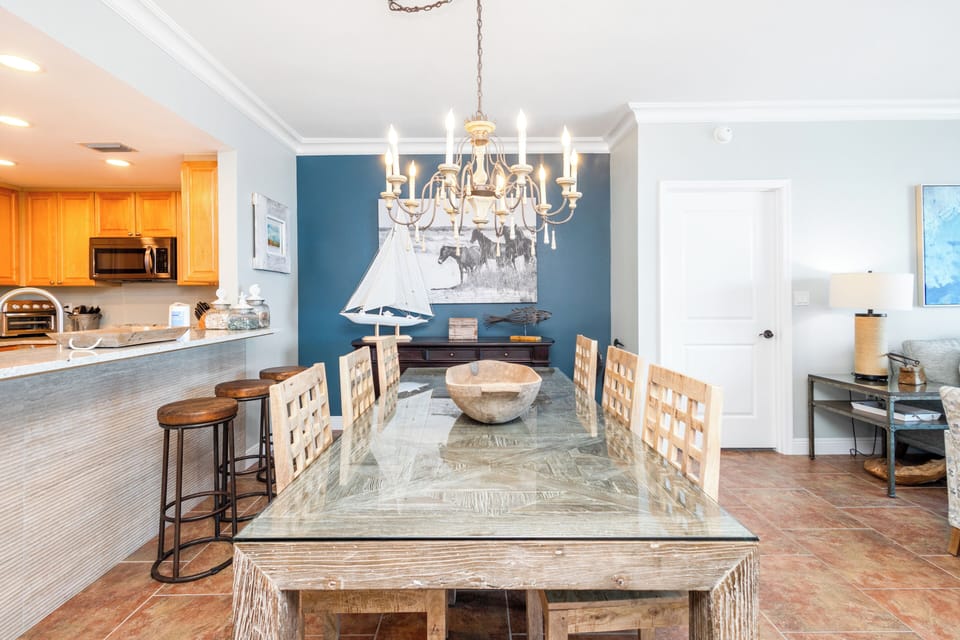 Gather around this beautifully styled dining space, where coastal charm meets comfort. Enjoy memorable meals under the chandelier's warm glow, with easy access to the fully-equipped kitchen.