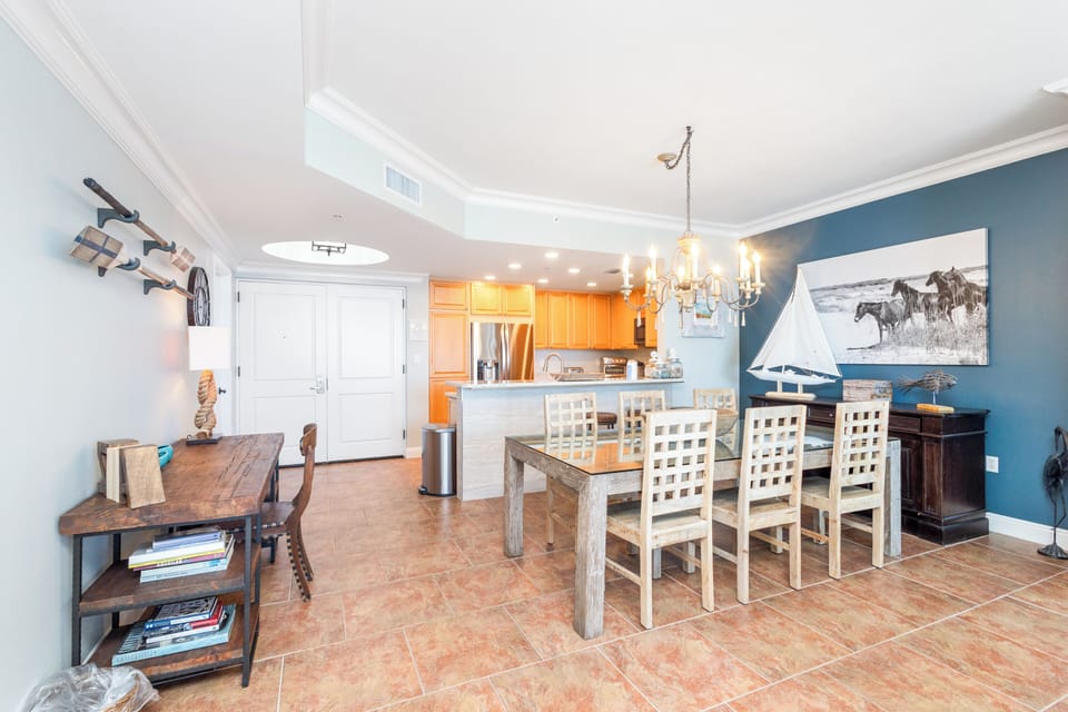Spacious dining area where you'll share memorable meals with loved ones, styled with coastal charm and nautical touches under a warm chandelier.
