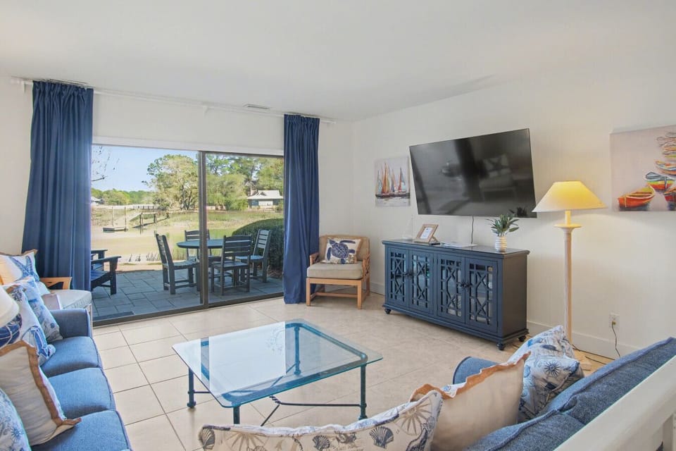 Spacious living area with a 65` Smart TV for streaming, a brand-new entertainment console (2026), and direct access to the back patio.