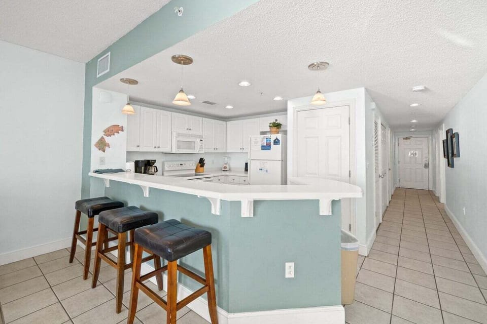 Featuring an eat-in bar perfect for casual dining or keeping the cook company, the space is equipped with all the essentials—including a microwave, dishwasher, stove, and oven—for effortless meal prep.
