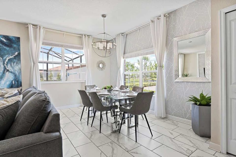 Dining room in a very well lit area and bright white curtains. Perfect blend of modern style and open-concept with the integrated living room, kitchen, and dining area.