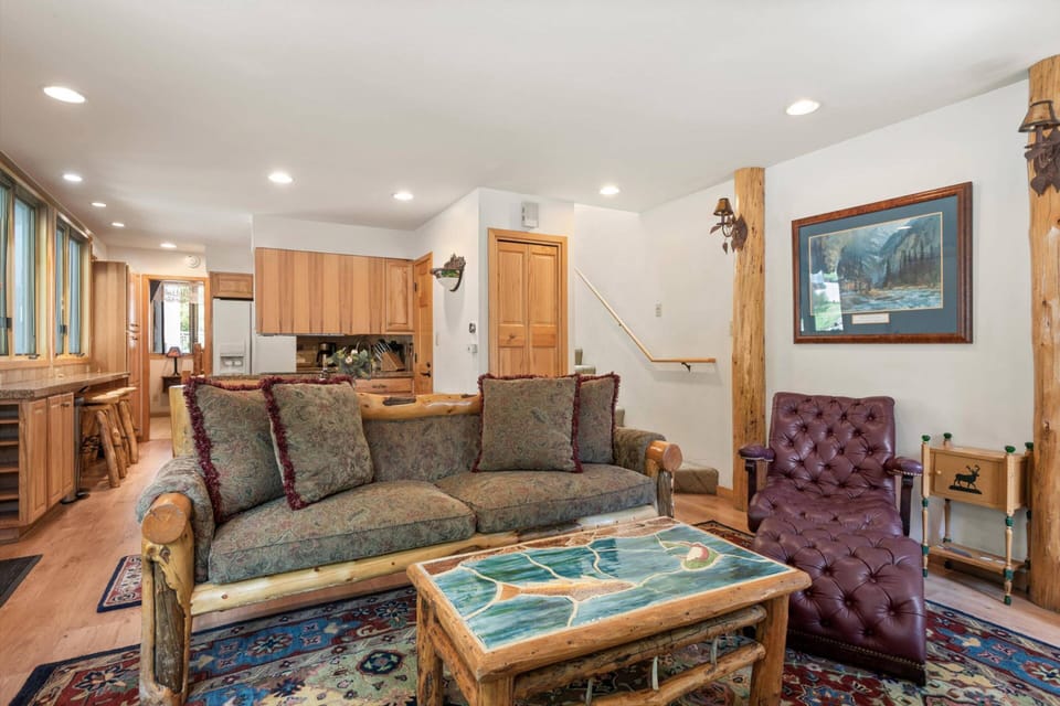 Open-concept living area with rustic log furniture and fully equipped kitchen - spacious main floor perfect for gathering and entertaining