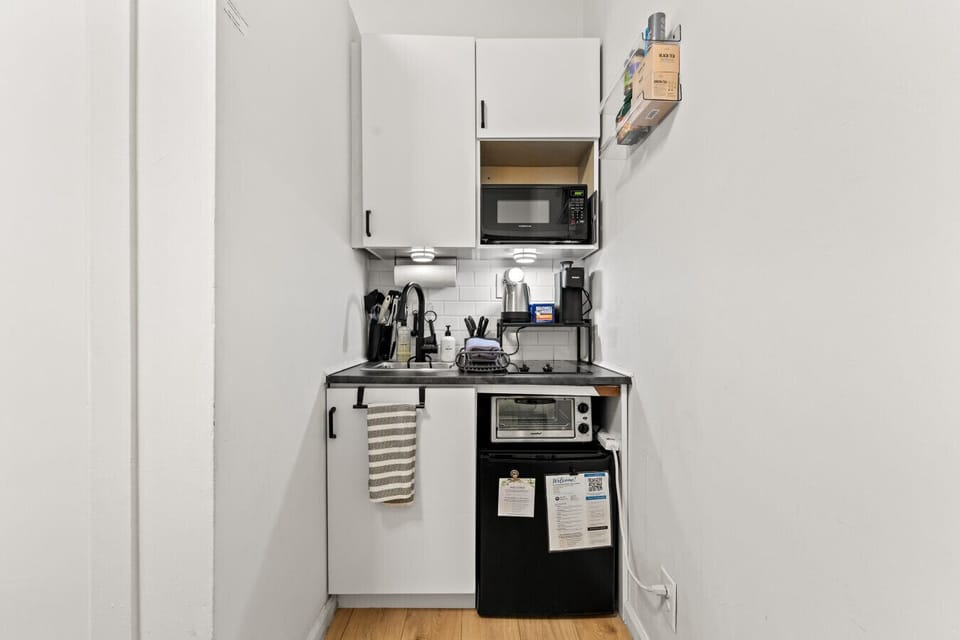 A tidy kitchenette with a fridge, microwave, and cooking basics, giving the space both convenience and function.