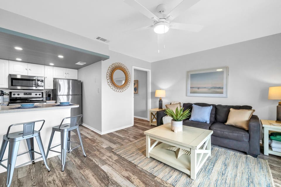 Relax in your stylish living area with modern furnishings, a fully equipped kitchen, and coastal-inspired decor that creates the perfect vacation atmosphere.
