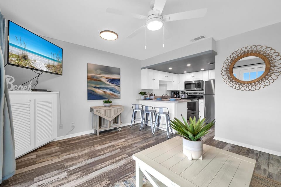 Your open-concept living space blends seamlessly into a modern kitchen, complete with coastal artwork and a dining bar for memorable meals together.