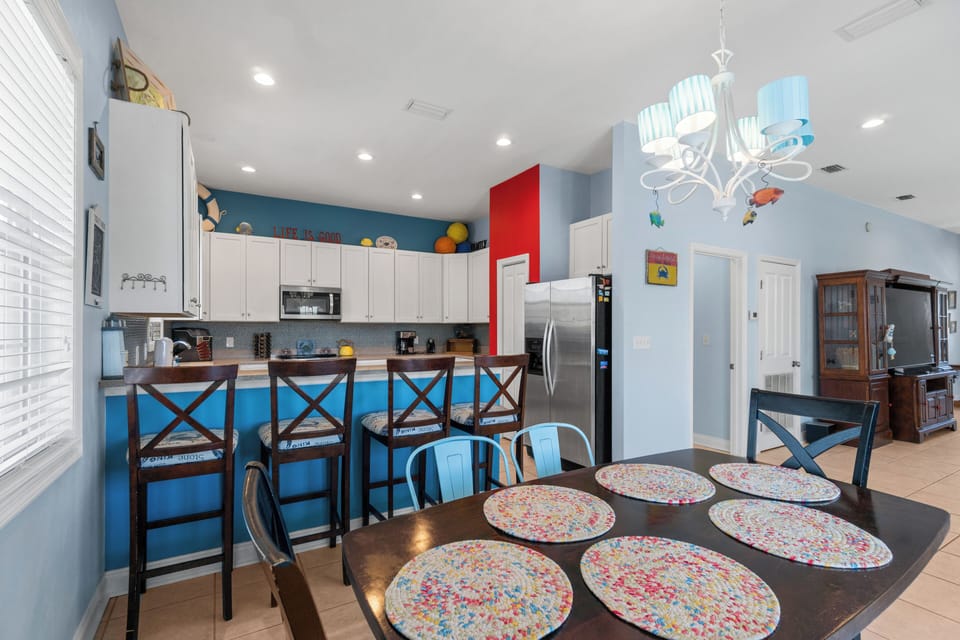 Gather around your bright, colorful kitchen where vibrant blue walls and cheerful placemats create the perfect backdrop for memorable meals together.