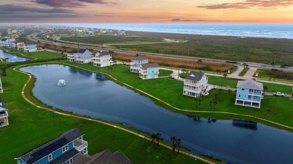 Aerial view of waterfront community showcasing canal access, upscale beach homes, and serene coastal surroundings.