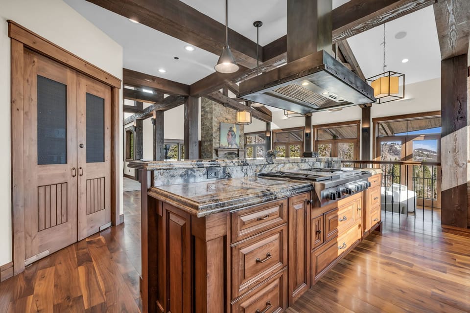 view of kitchen with the living room in the background, there are lots of windows and a luxurious marble countertop