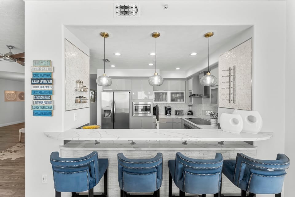 Modern kitchen with a marble countertop and blue bar stools for casual dining.
