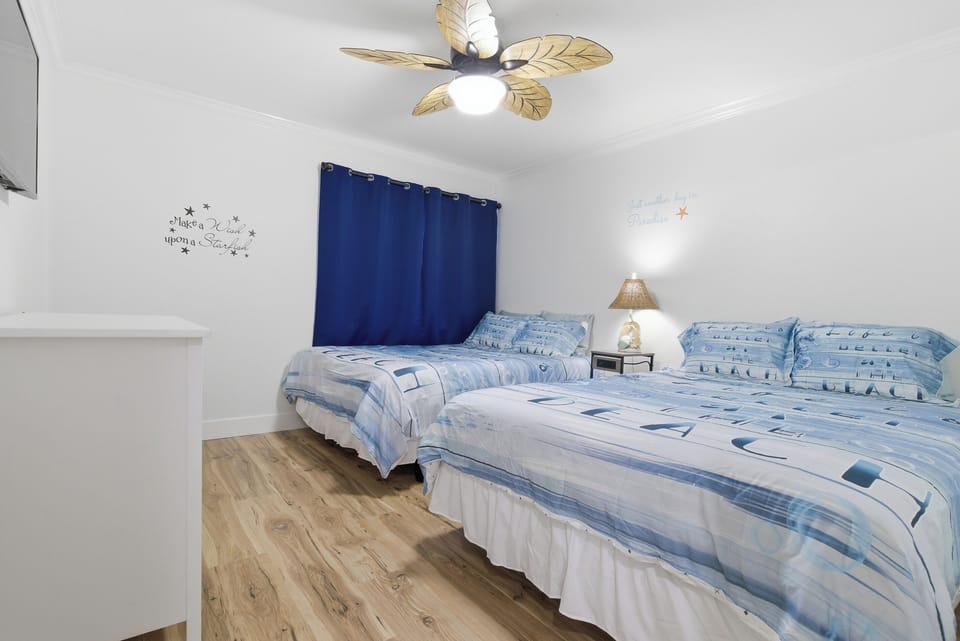 Lower Unit Bedroom #2
Two queen beds, Smart TV, mirrored closet, dresser, and coastal-inspired décor.